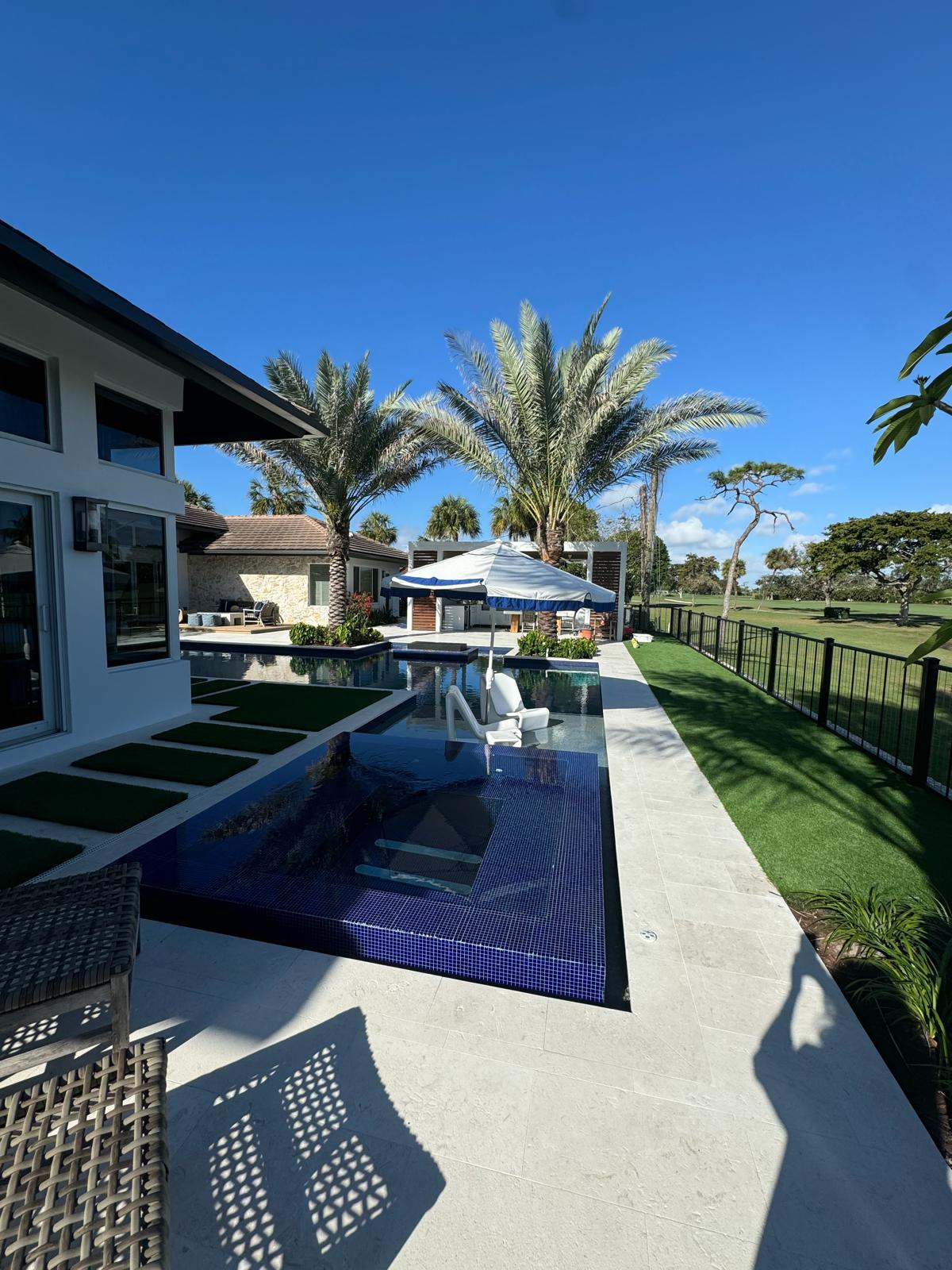 Piscina con jacuzzi en mosaico azul cobalto frente al golf